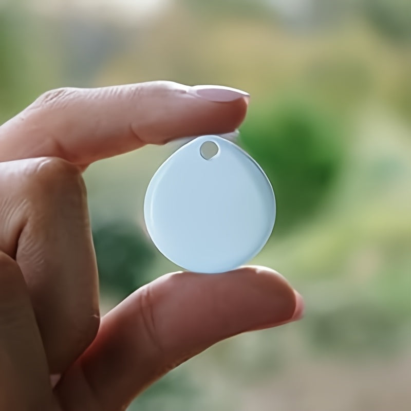 Round white Bluetooth tracker held between two fingers showing its compact size