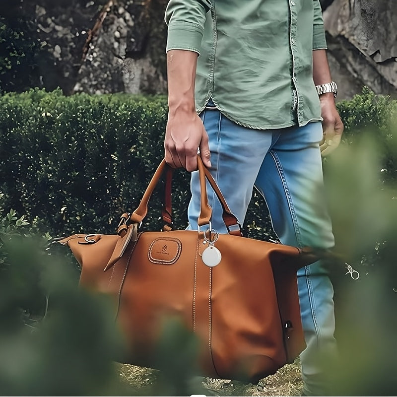 Teardrop-shaped Bluetooth key finder clipped to a brown travel bag outdoors